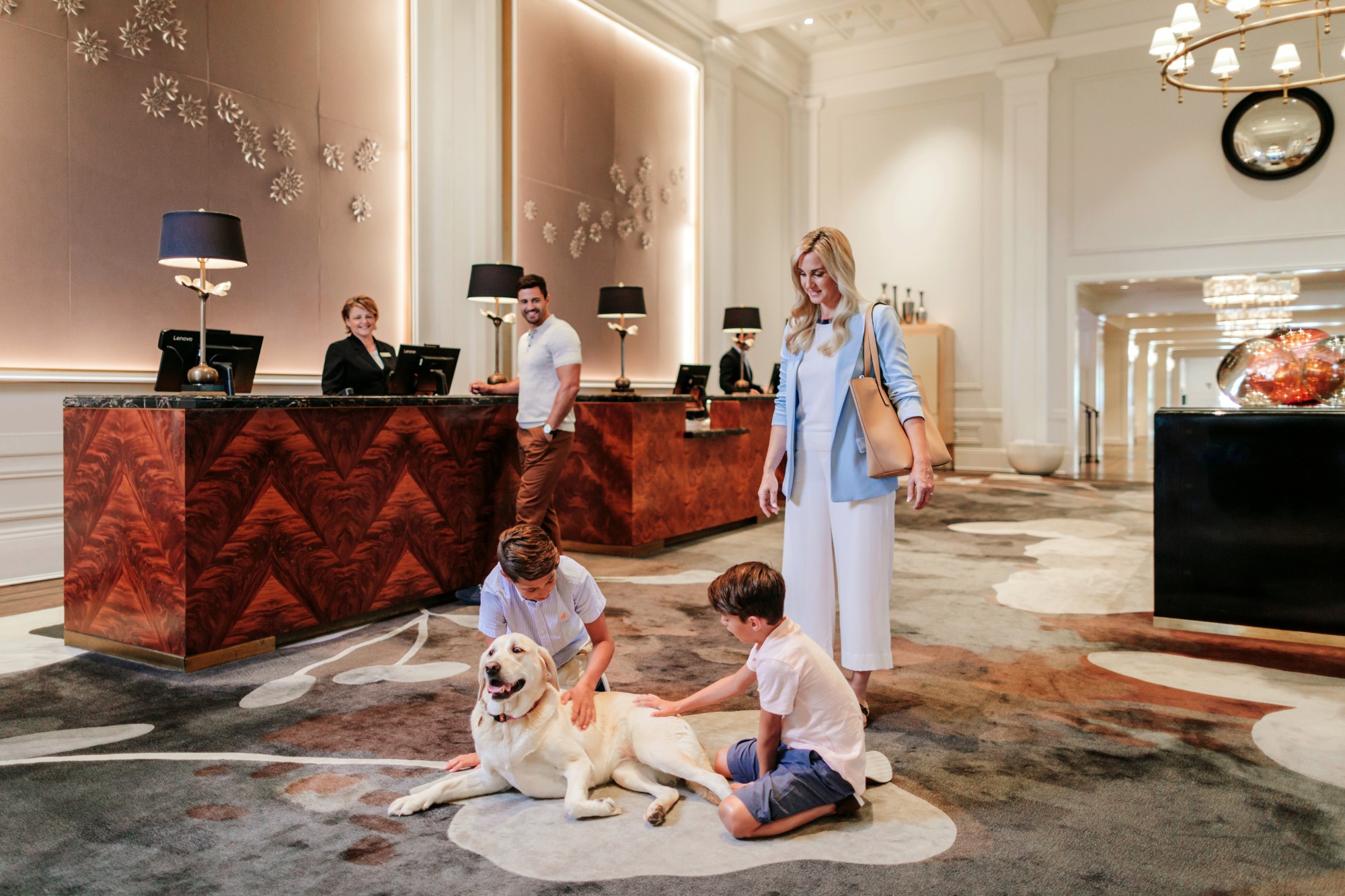 Dad checking into the hotel while his wife and kids play with the hotel dog