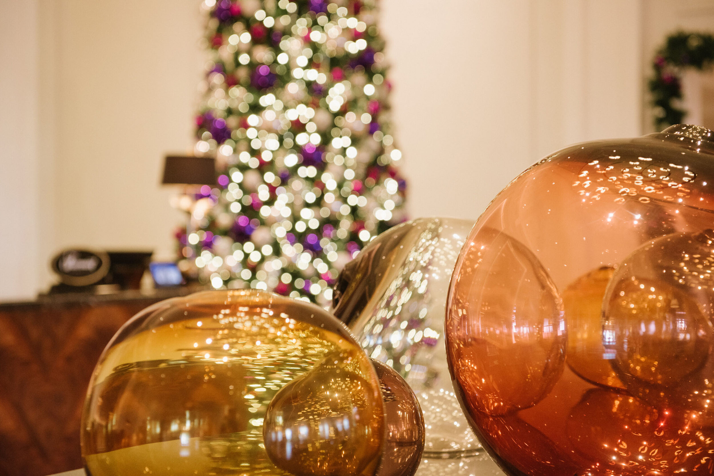 close up of christmas ornaments with christmas tree in the background